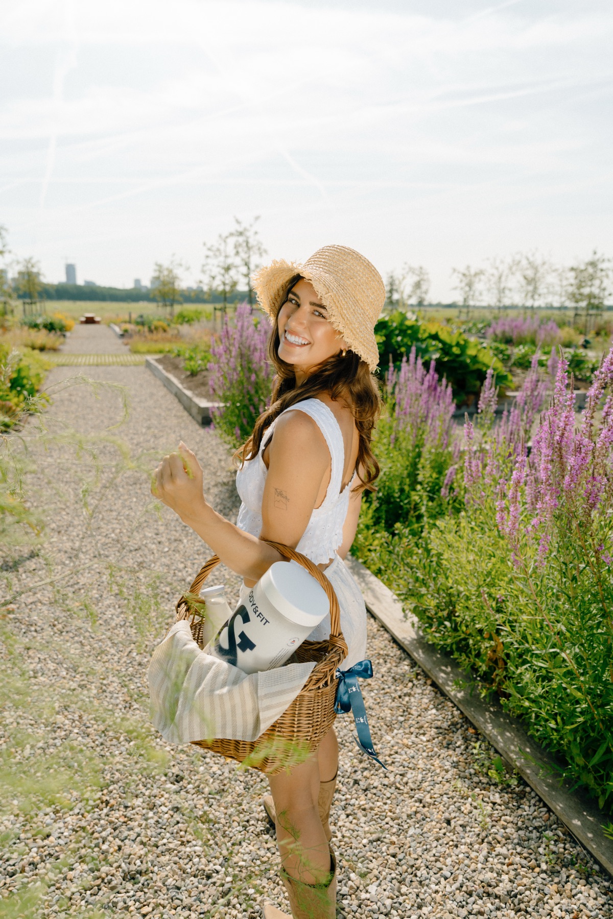 Lachende vrouw loopt door de moestuin met een mand vol product