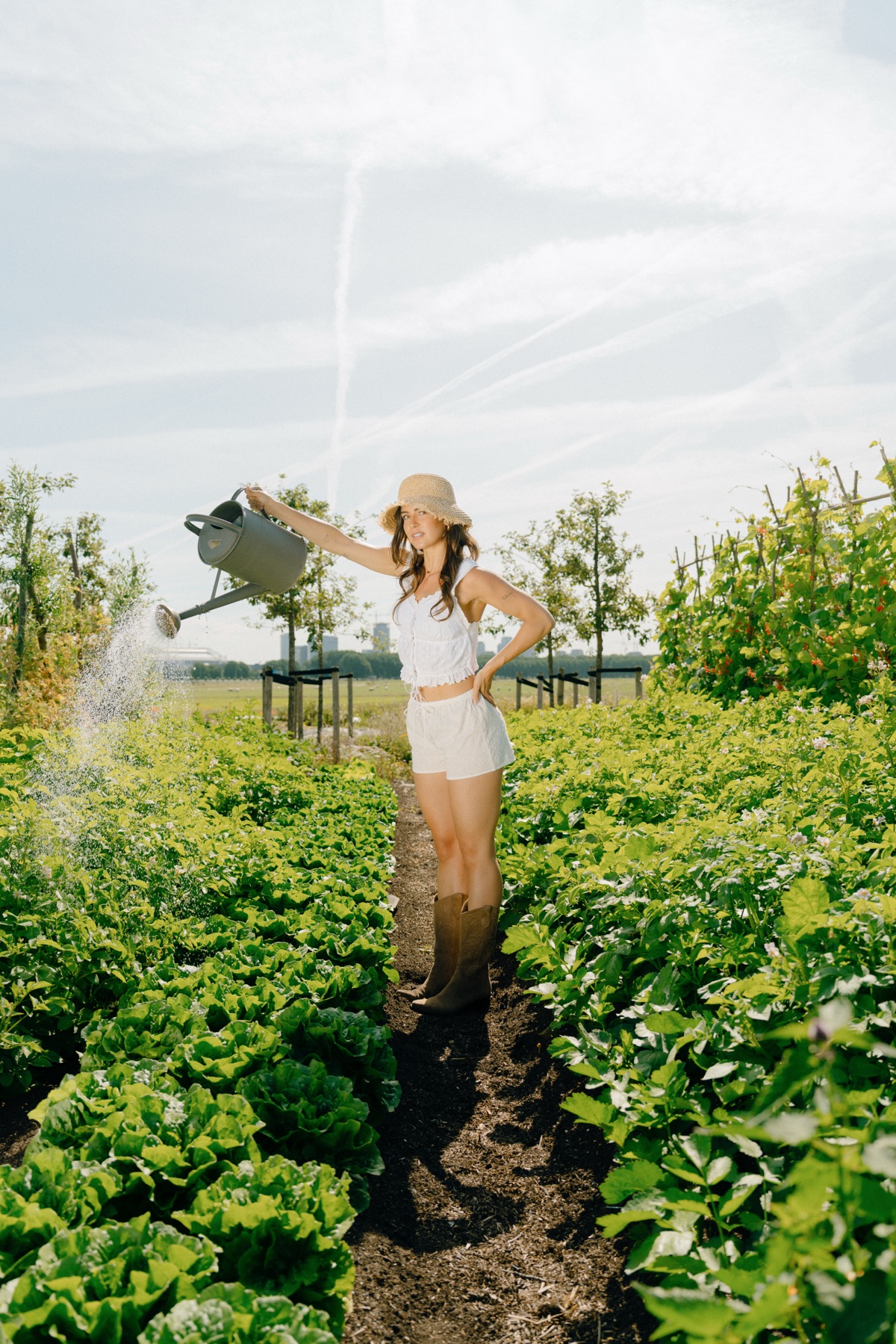 Vrouw geeft planten water met een gieter in de moestuin