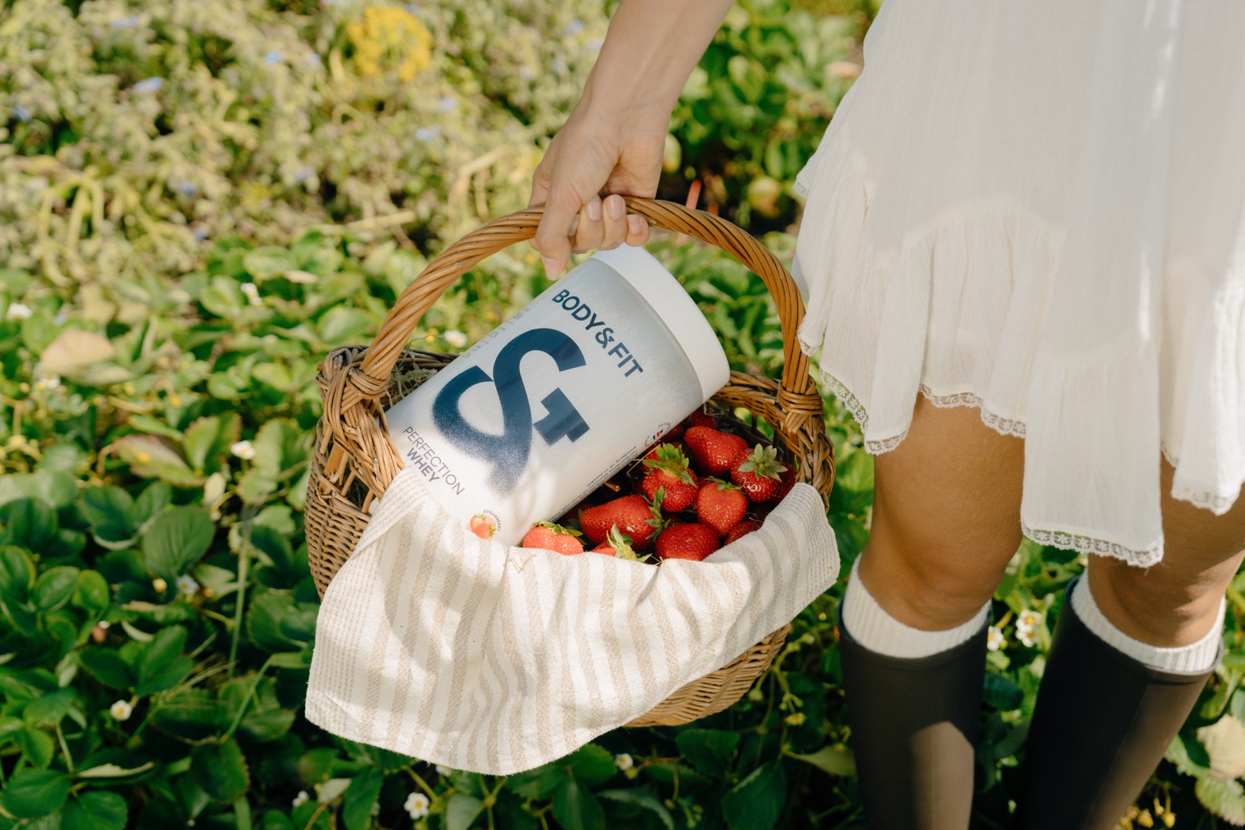 Rieten mand met aardbeien en een Body&Fit-bus