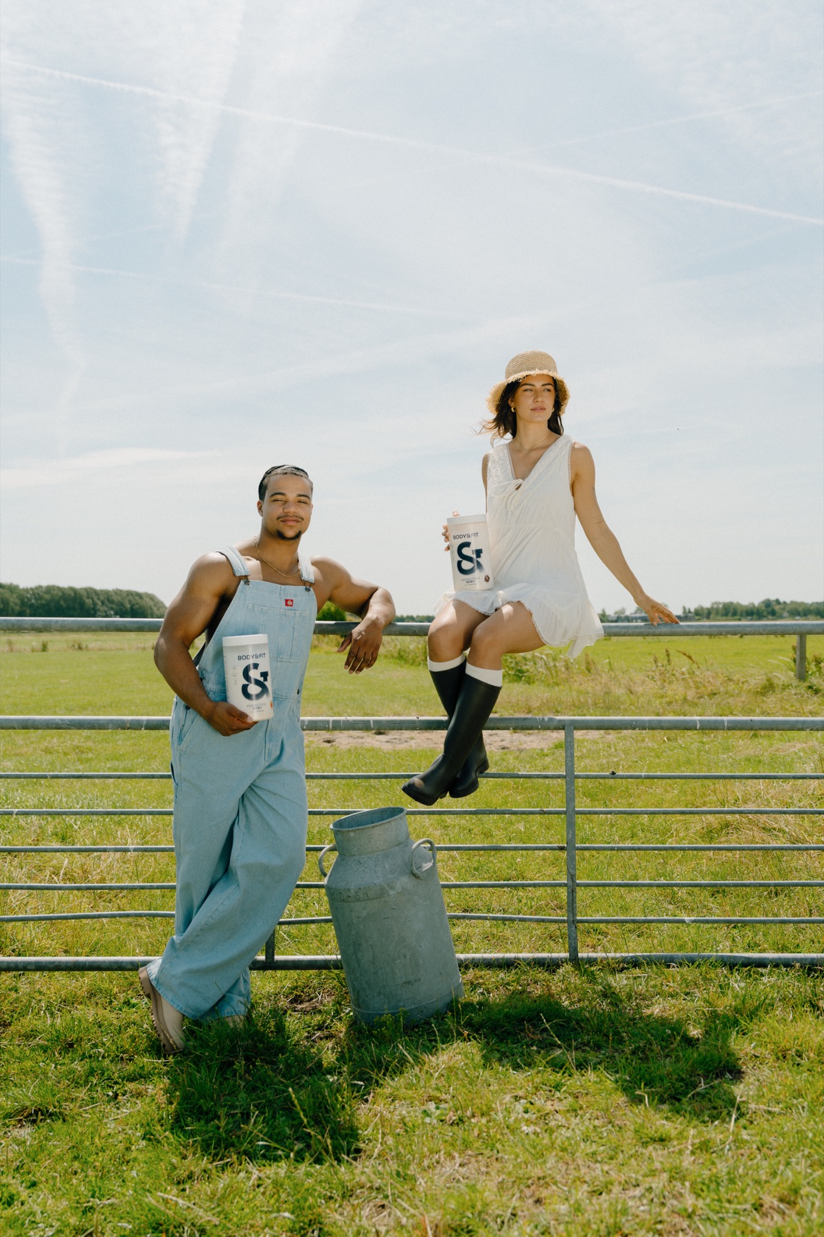 Man en vrouw bij een weidehek met een melkbus en product
